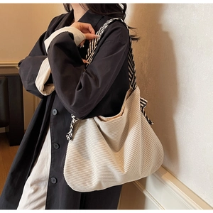 Detail of cream corduroy tote bag featuring a black and white striped shoulder strap