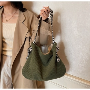 Detail of dark green corduroy tote bag with black and white woven rope shoulder straps