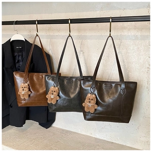 Close-up of leather tote bags in caramel and black with cute plush bear charms
