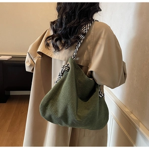 Detailed view of dark green corduroy tote bag with woven strap on a female model