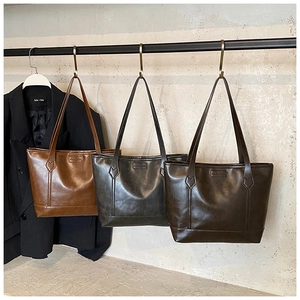 Detailed display of large leather tote bags in dark brown, grey black, and light tan