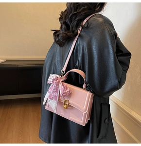 Pink crossbody bag with silk scarf detail worn by a model in a black leather jacket