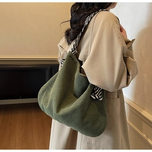 Detail of dark green corduroy tote bag with black and white striped shoulder strap