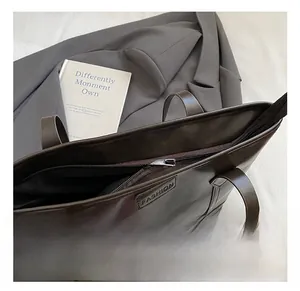 Detail shot of a dark brown tote bag with premium silver zipper and fashion embossed label