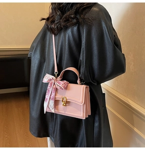Pink crossbody bag with gold ring buckle and heart print silk scarf detail on handle