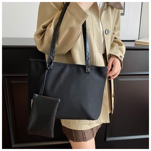 Detail of black suede tote bag and matching zipper pouch on model in khaki trench coat