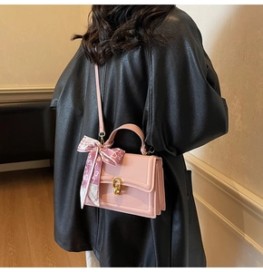 Detail of pink crossbody bag featuring gold twist lock and floral silk scarf accent
