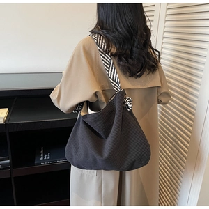 Detail of dark grey corduroy tote bag with zebra print strap on a fashion model