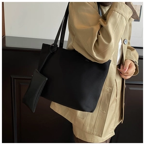 Detail of a black suede tote bag featuring a matching small rectangular coin purse pendant