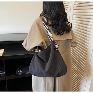 Detail of black corduroy tote bag featuring a stylish black and white striped woven strap