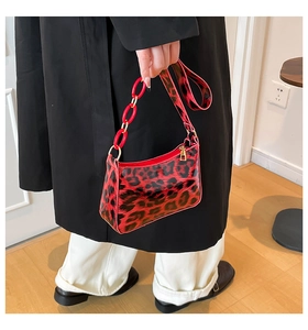 Detail of red leopard print underarm bag with decorative glossy red ring chain strap