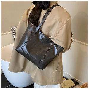 Detailed back view of a black leather tote bag with FASHION logo on a female model