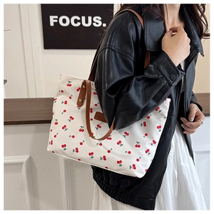 Detail view of canvas cherry print tote bag with brown leather straps for daily commute
