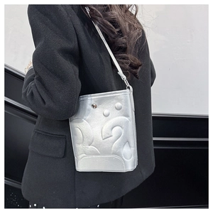 Détail du sac seau argenté avec motifs géométriques en relief et finition métallique