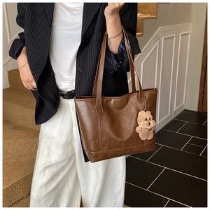 Detail of vintage brown tote bag with fashion embossing and plush bear charm decoration