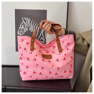 Detail der rosa Tasche mit Kirschmuster, braunen Ledergriffen und goldenen Nieten