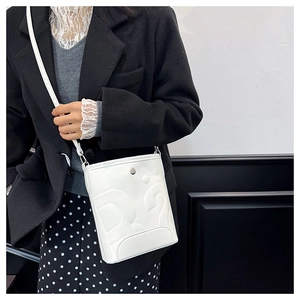 Détail du sac seau en cuir blanc avec logo D2 embossé et boucle métallique élégante