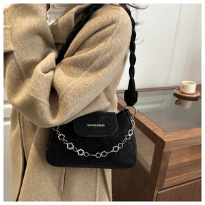 Detail of black suede flap bag with floral metal chain and woven shoulder strap
