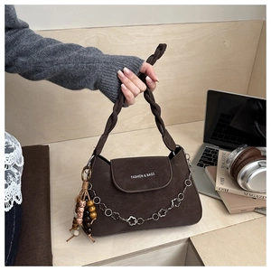 Detail of dark brown retro underarm bag with woven strap and colorful bead tassel
