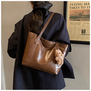 Close-up of brown matte PU leather tote bag featuring a cute plush bear charm