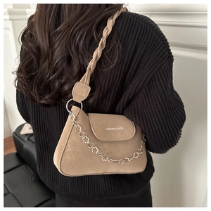 Detail of khaki suede underarm bag featuring a woven strap and floral metal chain