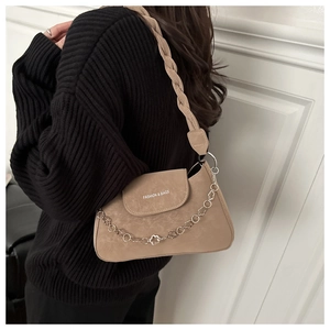 Detail of woven strap and silver chain on an apricot faux suede shoulder bag