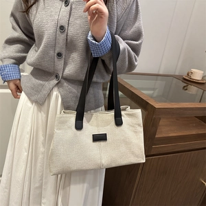 Sac fourre-tout minimaliste en toile blanc cassé avec lanières en cuir noir en situation