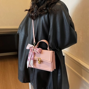 Pink crossbody handbag with gold buckle and heart print scarf shown on a model