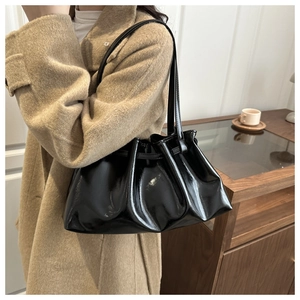Detail einer schwarzen glänzenden Lackleder-Einkaufstasche mit elegantem Falten-Design und Trägern