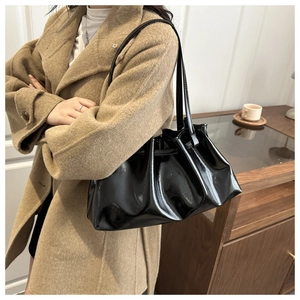 Detailaufnahme der schwarzen glänzenden Achseltasche mit stilvollen Falten-Details