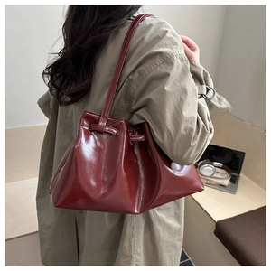 Detail of burgundy glossy leather tote bag with drawstring texture and long shoulder strap