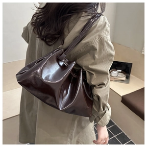 Detail of glossy deep brown pleated tote bag with mirror finish and slim leather strap