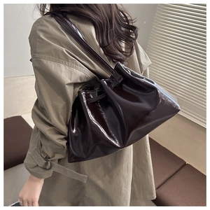 Detail of dark brown glossy patent leather tote with pleated drawstring and dual straps