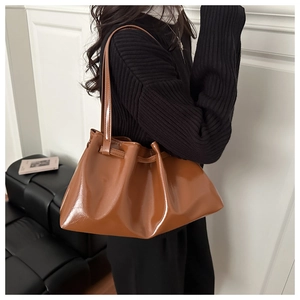 Close-up of caramel brown glossy leather tote bag with elegant pleated cloud design