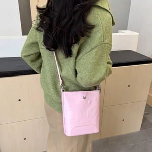 Sac seau rose avec relief B élégant, porté à l'épaule dans un cadre moderne et chic