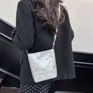 Sac seau argenté avec motifs gaufrés et finition métallisée porté par un modèle