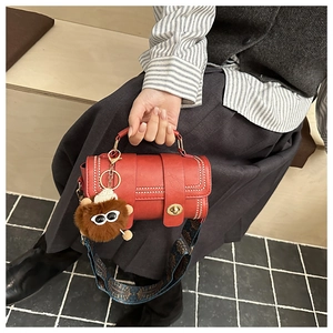 Detail of red cylinder bag with metallic studs and colorful ethnic jacquard strap