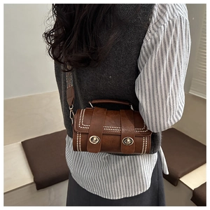Detail of vintage brown PU leather crossbody bag with gold studs and jacquard strap