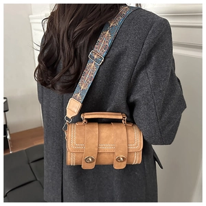 Detail of vintage brown cylindrical bag with double metal locks and ethnic woven strap