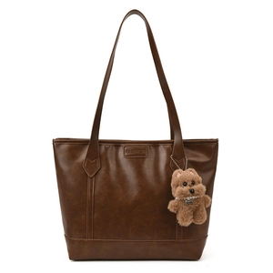 Large dark brown leather tote bag with fashion embossing and plush dog charm accessory