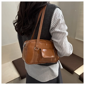 Close-up of caramel brown PU leather shoulder bag with white contrast stitching details