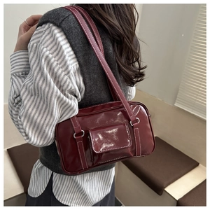 Detail view of burgundy retro leather handbag with white stitching and silver hardware