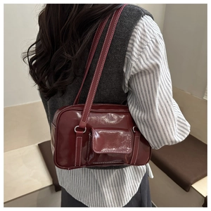Close-up of retro burgundy shoulder bag with white contrast stitching and shiny leather