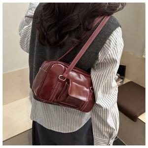 Close-up of a dark red retro underarm bag with white contrast stitching and front flap pocket
