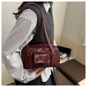 Detail of burgundy rectangular shoulder bag with white contrast stitching and side pocket