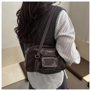 Detail of dark brown glossy shoulder bag with contrast stitching and front flap pocket