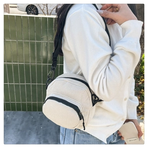 Detail of white corduroy mini crossbody bag with double zippers and black nylon strap