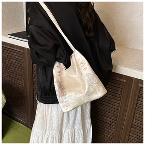Close-up of Chinese style embroidery on a cream shoulder bag with elegant tassel detail