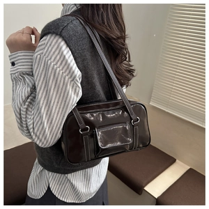 Detail of dark brown glossy shoulder bag with contrast stitching and metal D-ring