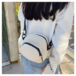 Detail of off-white corduroy crossbody bag with double zipper and black strap